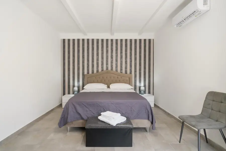 Letto matrimoniale e sedia sotto il climatizzatore