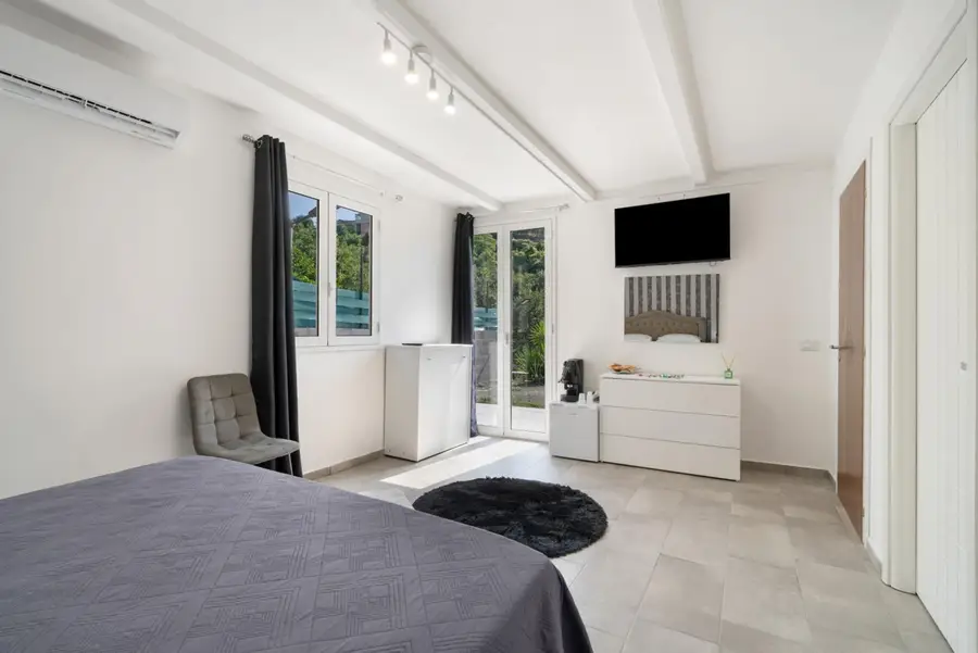 TV, cassettiera e porta-finestra sul patio