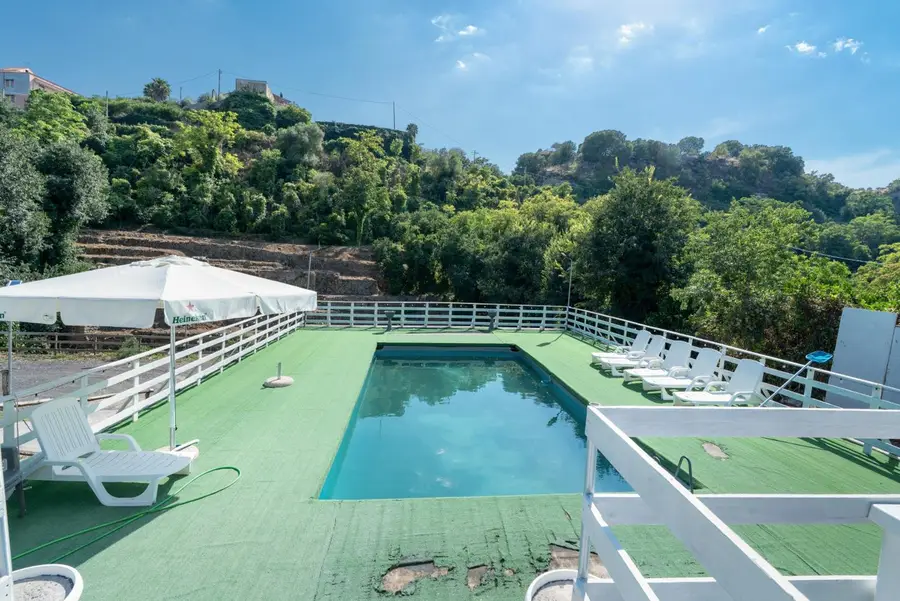 La piscina all'aperto con lettini e ombrellone, circondata dagli alberi